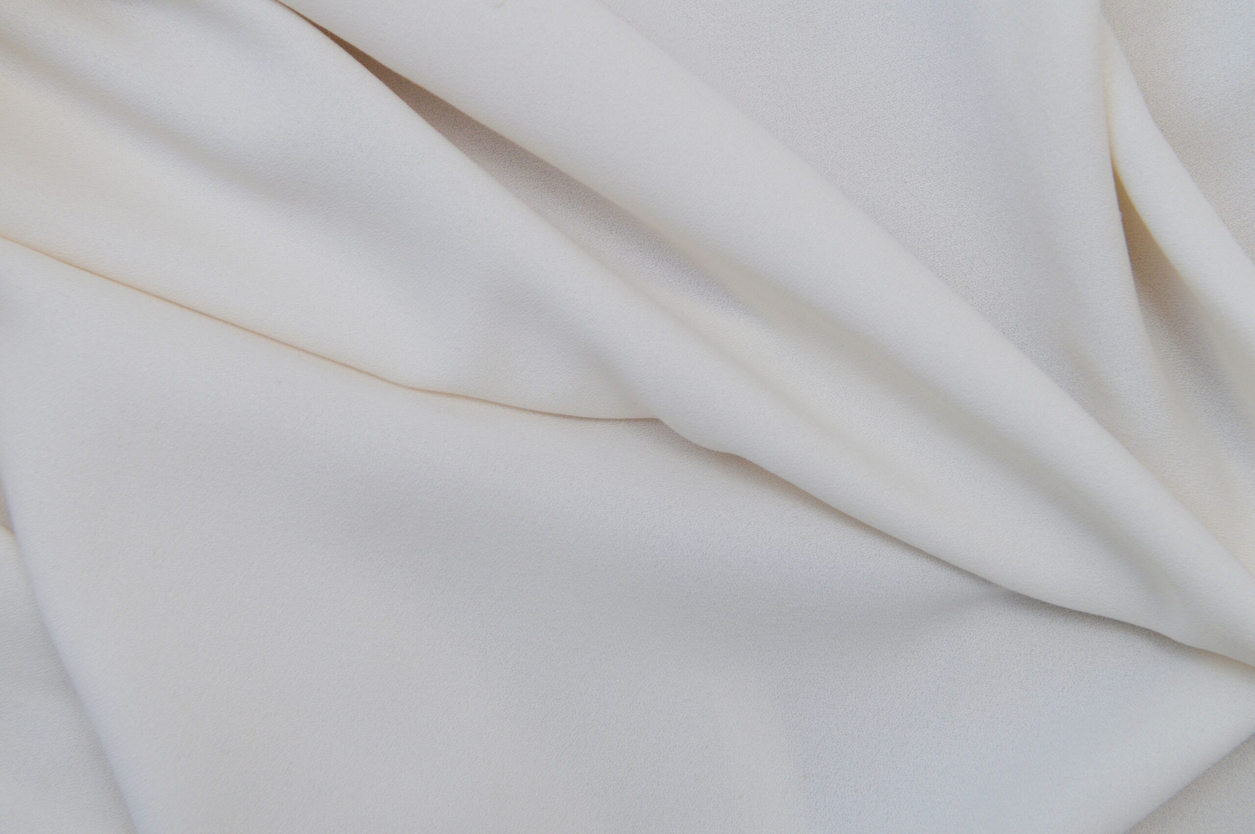 Close-up of elegant white fabric with smooth folds and texture details.